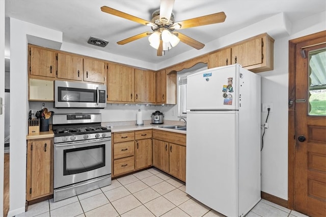 kitchen with appliances with stainless steel finishes, sink, light tile patterned floors, and ceiling fan