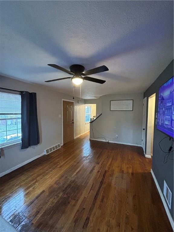 unfurnished living room with ceiling fan, dark hardwood / wood-style flooring, and a textured ceiling