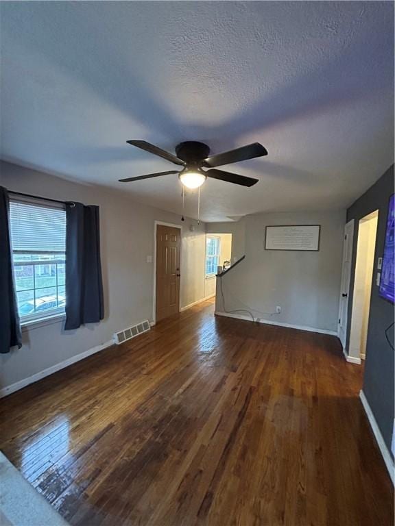 empty room with ceiling fan, dark hardwood / wood-style flooring, and a textured ceiling