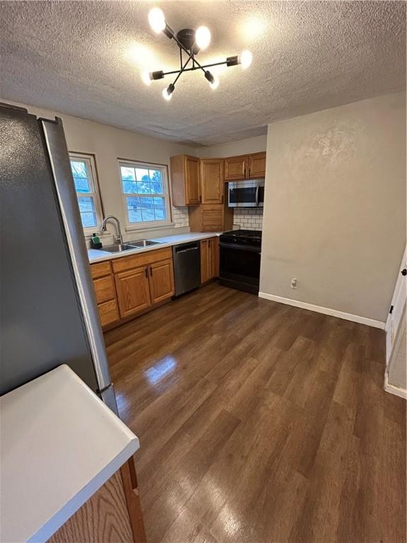 kitchen featuring sink, dark hardwood / wood-style floors, a chandelier, a textured ceiling, and appliances with stainless steel finishes