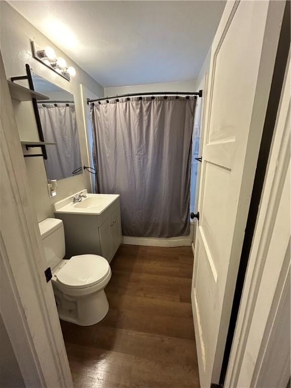 bathroom featuring hardwood / wood-style floors, vanity, curtained shower, and toilet