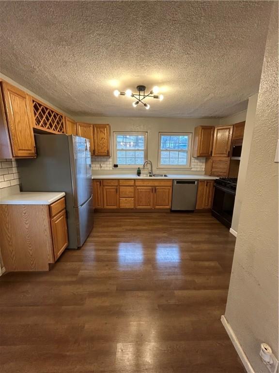 kitchen featuring appliances with stainless steel finishes, tasteful backsplash, dark hardwood / wood-style floors, and sink