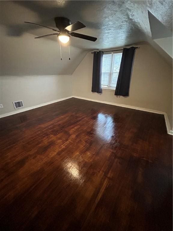 bonus room with wood-type flooring, a textured ceiling, and vaulted ceiling