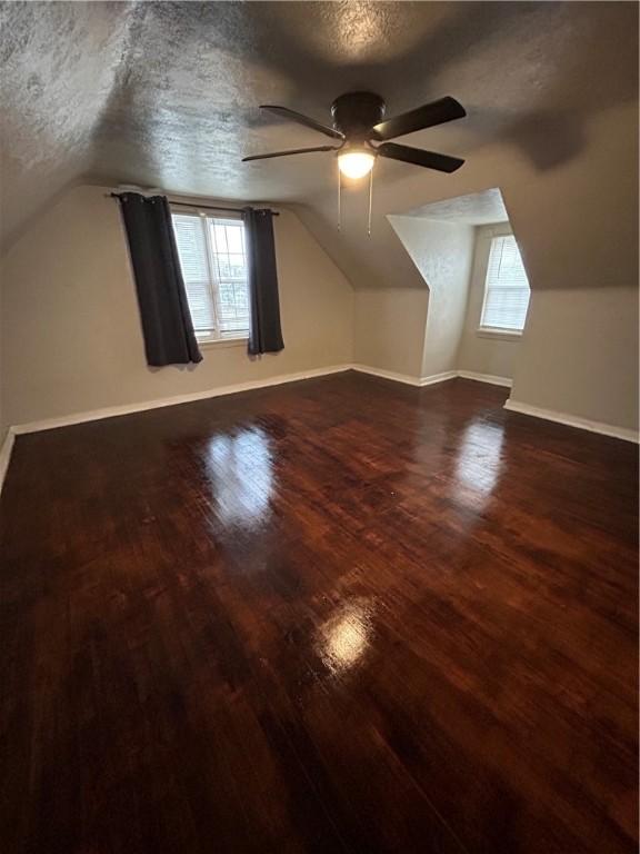 additional living space featuring lofted ceiling, ceiling fan, hardwood / wood-style floors, and a textured ceiling