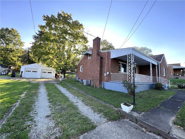 view of side of property with central air condition unit, a garage, covered porch, an outdoor structure, and a yard