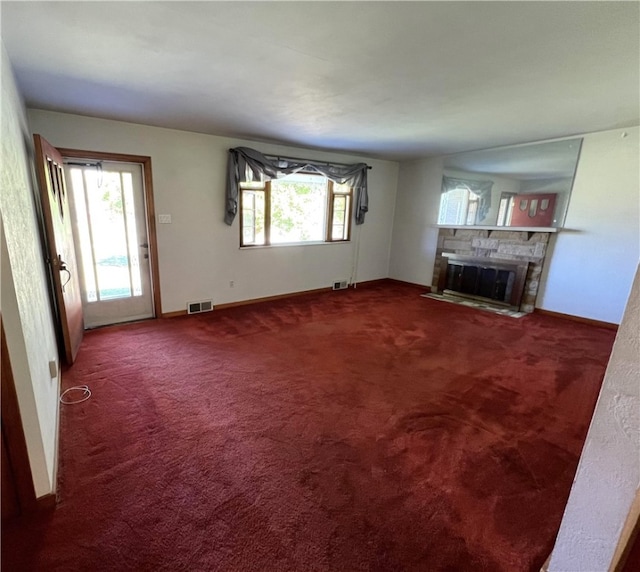 unfurnished living room with a fireplace and dark colored carpet