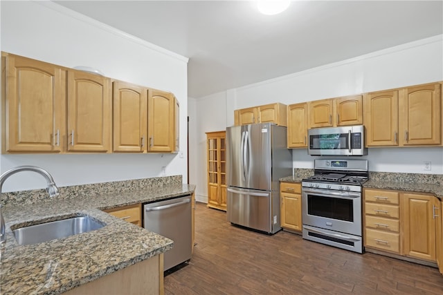 kitchen featuring appliances with stainless steel finishes, dark stone countertops, dark wood-type flooring, crown molding, and sink