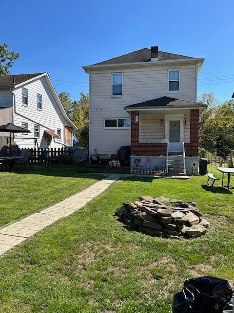 back of property featuring a lawn and an outdoor fire pit