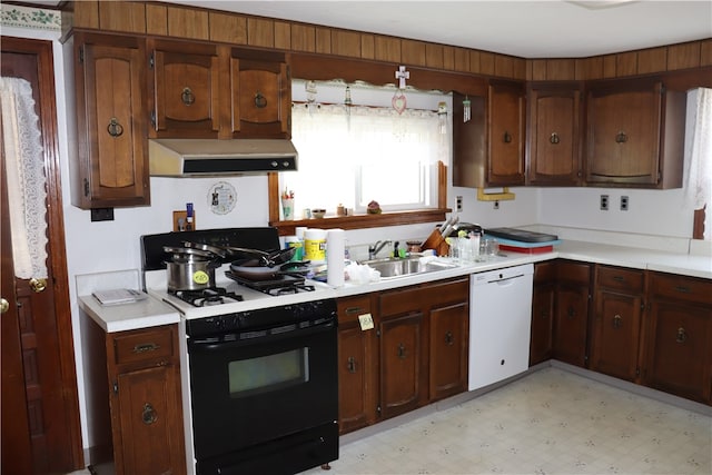 kitchen with dark brown cabinetry, white appliances, and sink