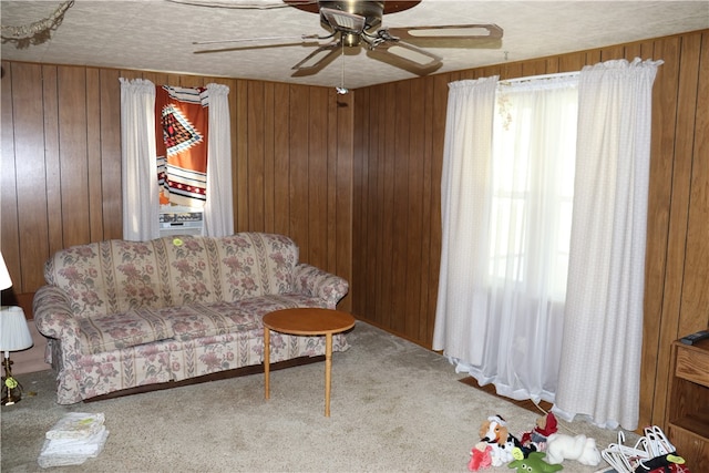 unfurnished living room with carpet, wooden walls, and ceiling fan