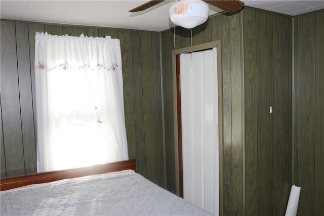 unfurnished bedroom featuring a closet, wooden walls, and ceiling fan