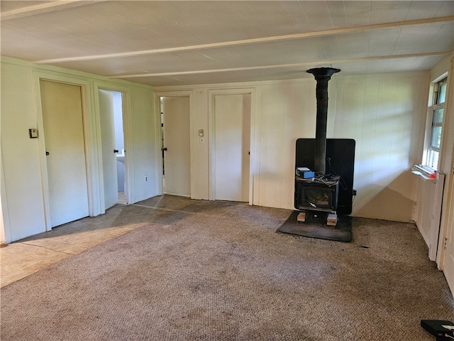 unfurnished living room featuring carpet floors and a wood stove