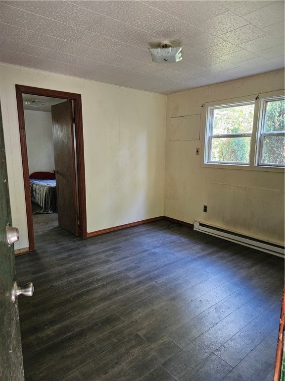 empty room with baseboard heating and dark hardwood / wood-style floors