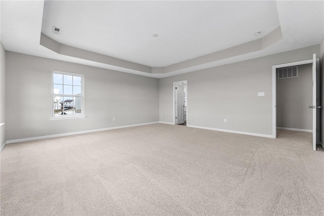 unfurnished room with light carpet and a tray ceiling