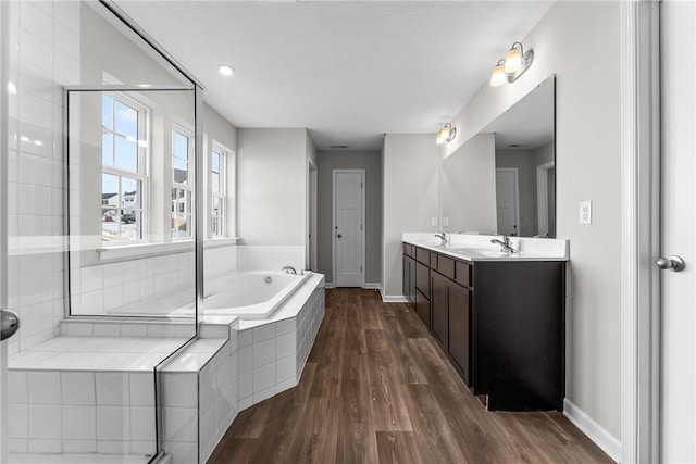 bathroom featuring vanity, hardwood / wood-style flooring, and a relaxing tiled tub