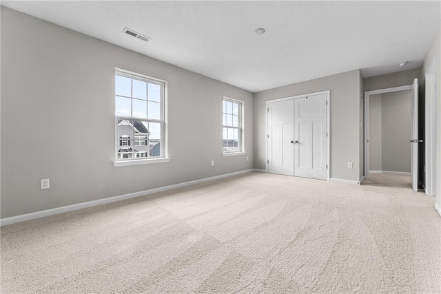 unfurnished bedroom with light carpet and a closet