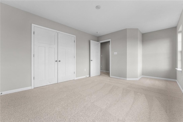 unfurnished bedroom featuring a closet and light colored carpet