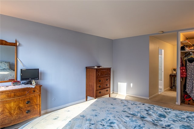 bedroom with light colored carpet, a closet, and a spacious closet