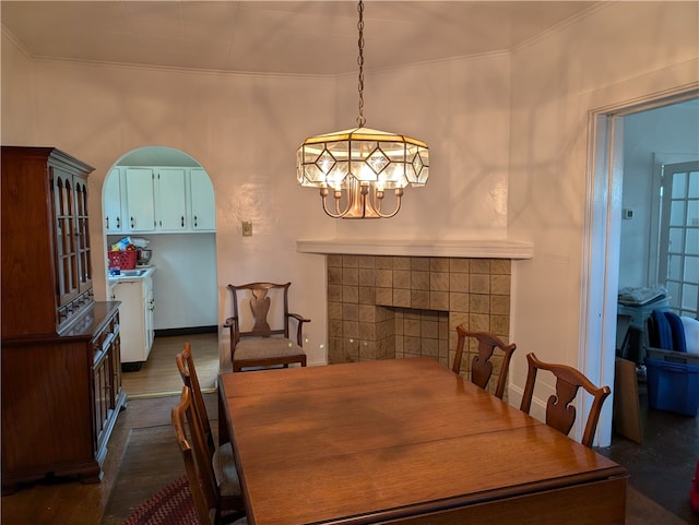 dining area featuring a fireplace, crown molding, and a notable chandelier