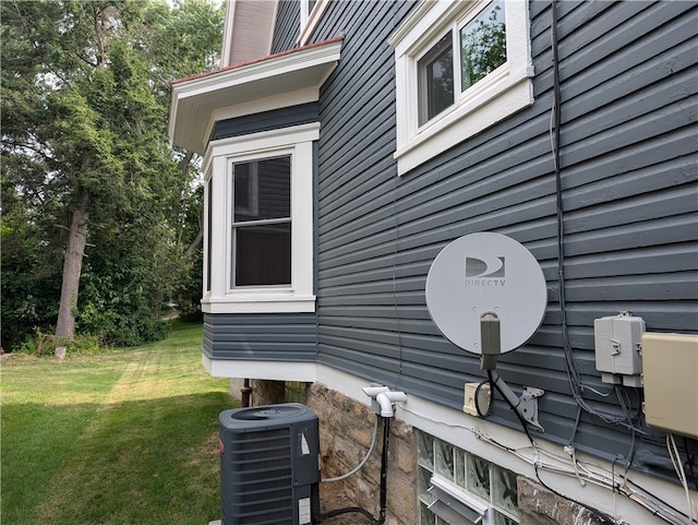 view of property exterior with central air condition unit and a lawn