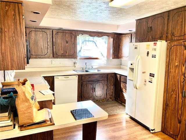 kitchen with a textured ceiling, sink, light hardwood / wood-style floors, and white appliances