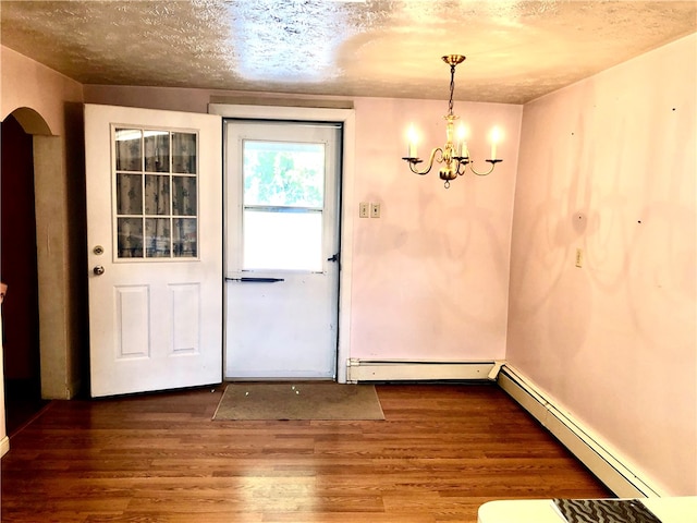 doorway to outside featuring an inviting chandelier, wood-type flooring, a textured ceiling, and baseboard heating