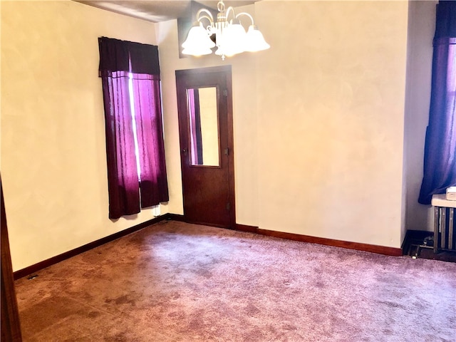 empty room featuring carpet flooring and a chandelier