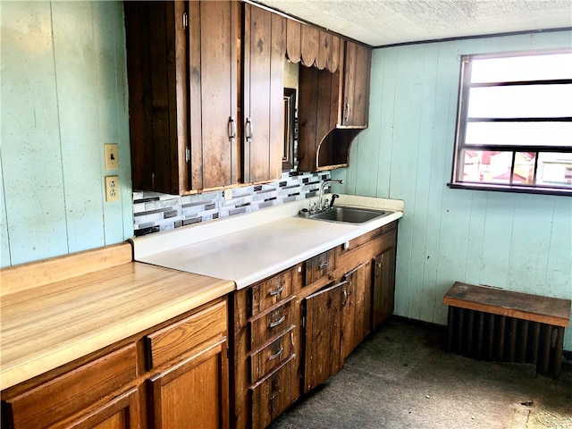 kitchen with dark colored carpet, wood walls, sink, and tasteful backsplash