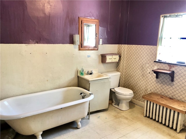 bathroom with radiator, a bathtub, sink, tile walls, and toilet