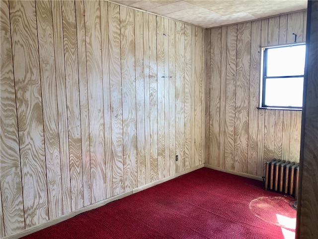 unfurnished room featuring radiator, carpet, and wooden walls