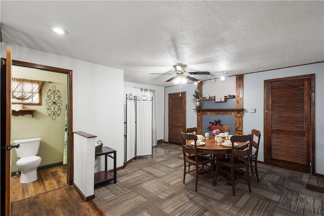 dining area with ceiling fan, a textured ceiling, and dark wood-type flooring