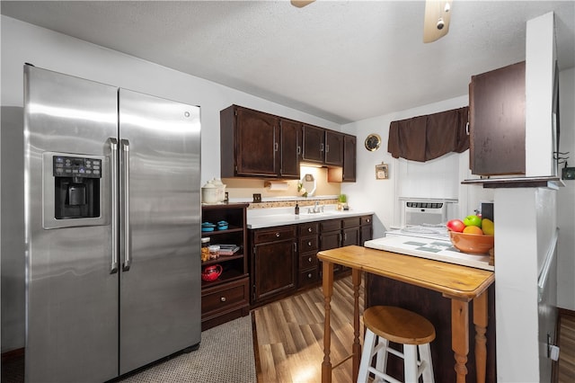 kitchen with dark brown cabinetry, cooling unit, stainless steel fridge, sink, and light wood-type flooring