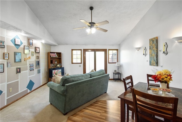 living room with light hardwood / wood-style flooring, a textured ceiling, high vaulted ceiling, and ceiling fan