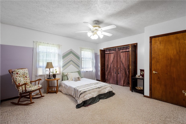 carpeted bedroom featuring ceiling fan and a textured ceiling