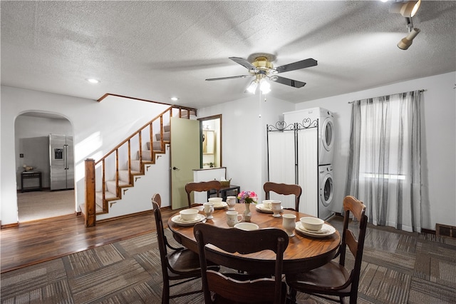 dining space with a textured ceiling, stacked washer and dryer, dark hardwood / wood-style flooring, and ceiling fan