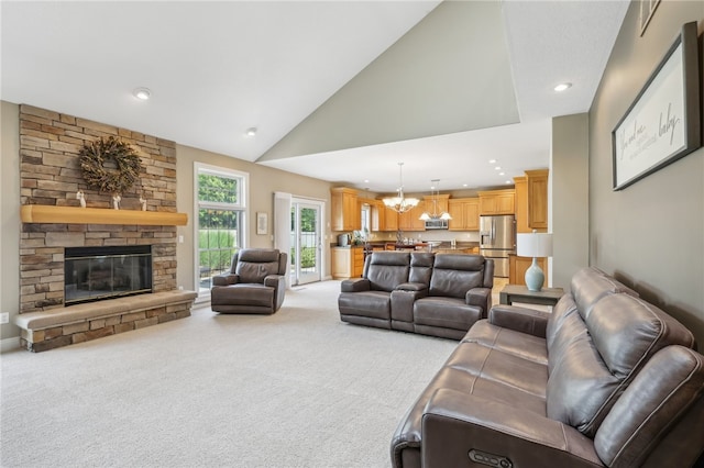 living room with a notable chandelier, high vaulted ceiling, a fireplace, and light carpet