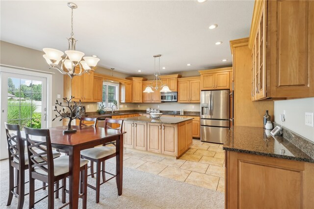 kitchen with stainless steel appliances, dark stone countertops, a wealth of natural light, and a center island