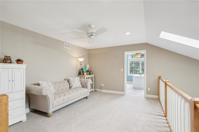 living area with light carpet, ceiling fan, and lofted ceiling with skylight