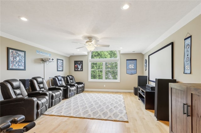 home theater room featuring light hardwood / wood-style floors, ceiling fan, and crown molding