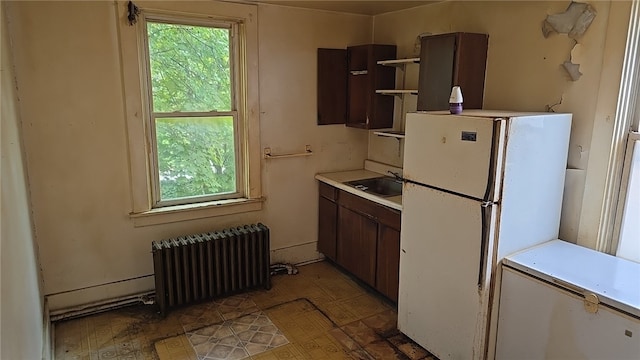 kitchen with radiator, white refrigerator, dark brown cabinetry, and sink