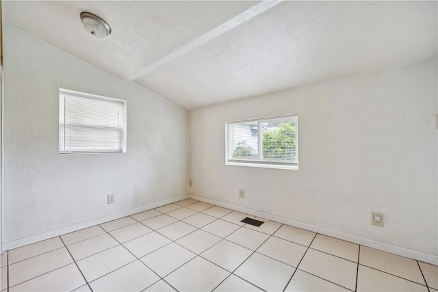 tiled empty room with a textured ceiling and lofted ceiling