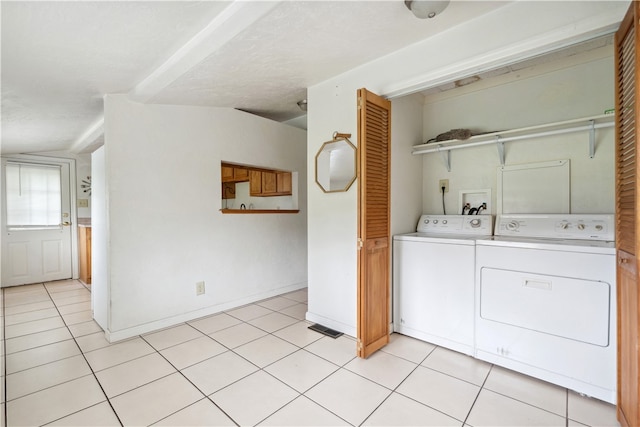 clothes washing area with washer and clothes dryer, light tile patterned flooring, and a textured ceiling