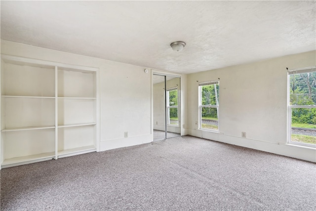 spare room with carpet floors, a textured ceiling, and a healthy amount of sunlight