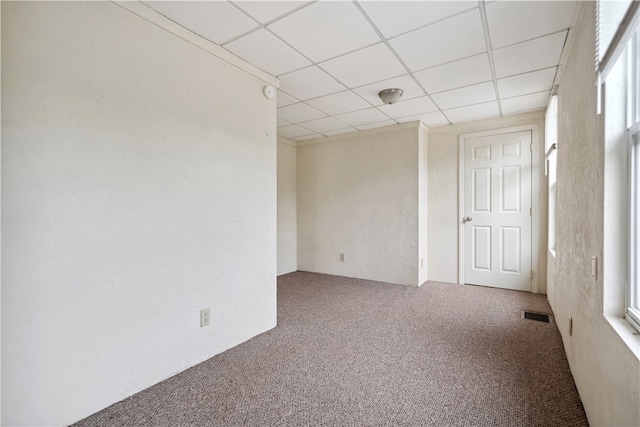 carpeted spare room featuring a drop ceiling