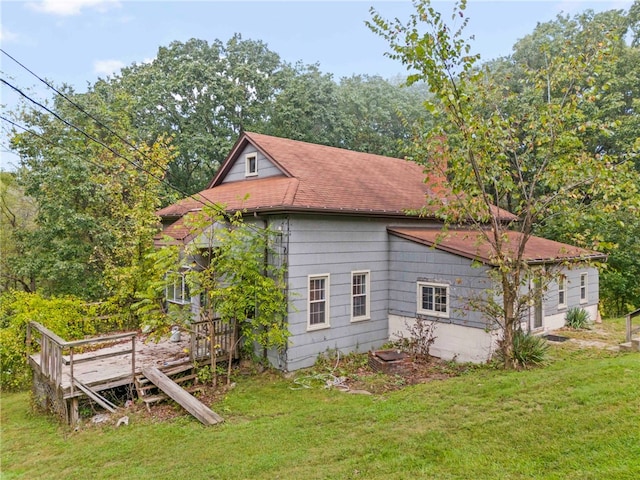 view of home's exterior featuring a yard, a wooden deck, and a shingled roof