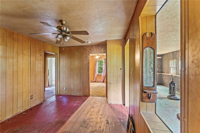 corridor with wood walls, a textured ceiling, and dark hardwood / wood-style flooring