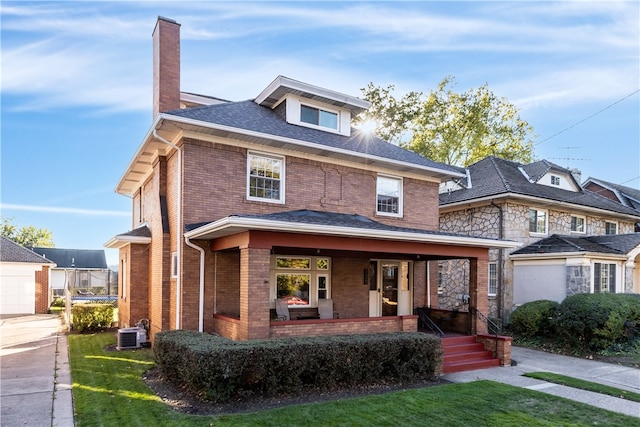 view of front of property featuring a front lawn, covered porch, and central AC