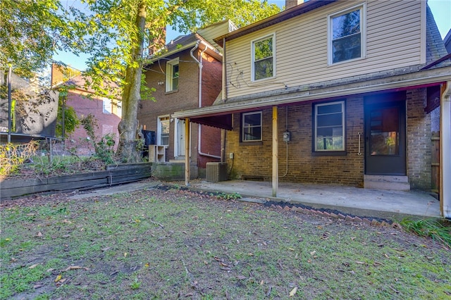 back of house featuring a lawn, a porch, and central air condition unit