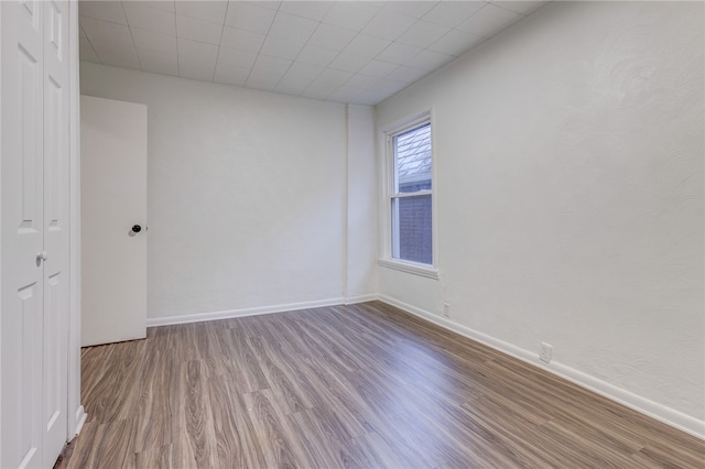 empty room with a drop ceiling and wood-type flooring