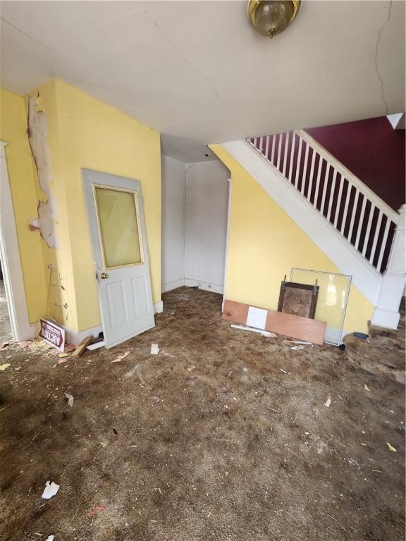 unfurnished living room featuring stairway